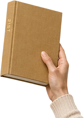 A hand holding a tan linen hardcover photo book with the title 21ST foil stamped down the spine.